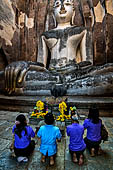 Buddist worshippers pay homage to the impressive 15 meter high seated Buddha named Phra Achana enshrined at Wat Si Chum - Old Sukhothai - Thailand. 